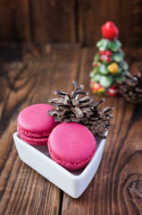 Pink macaroons with christmas decorations on wooden background