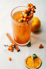 Warm sweet organic tea with sea buckthorn berries, thyme and honey. White background, natural lighting. Horizontal composition with copy space. Concept of beauty in simplicity.