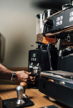Fototapeta Bar tender pressing ground coffee into portafilter by tamper to making coffee