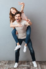 Full length portrait of a cheerful man carrying girlfriend