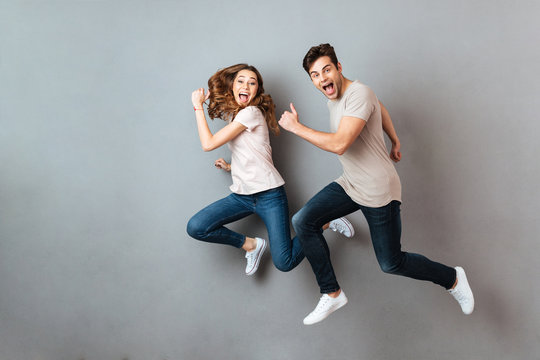 Full length portrait of a cheerful young couple jumping