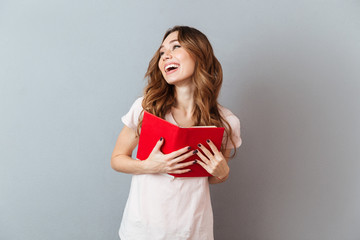 Portrait of a pretty laughing girl holding book