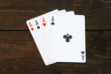 play casino card games on the Brown rough grunge texture of wood table or desk vintage color dark tone style view from top, gang of four aces, clubs on above. Four of a kind of aces poker.