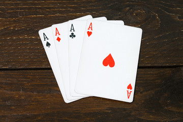play casino card games on the Brown rough grunge texture of wood table or desk vintage color dark tone style view from top, gang of four aces, hearts on above. Four of a kind of aces poker.