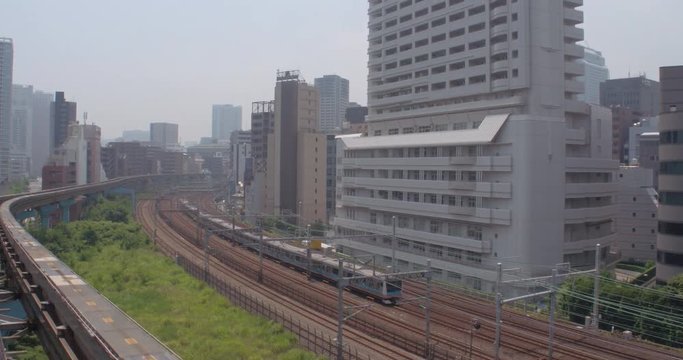 TOKYO, JAPAN – JUNE 2016 : Video shot of train moving in central Tokyo with tall buildings and car traffic in view