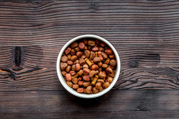 dry dog food in bowl on wooden background top view