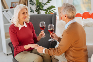 Sweet conversation. Selective focus on a joyful elderly woman smiling cheerfully while sitting in front of her husband and listening to him during a romantic date.