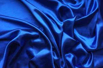 Blue satin, silky fabric, wave, draperies. Beautiful textile backdrop. Close-up. Top view