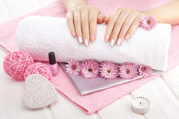 beautiful pink manicure with chrysanthemum flower and towel on the white wooden table. spa