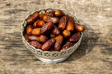 Dates fruit on a silver bowl on wooden table. The Muslim feast of the holy month of Ramadan Kareem