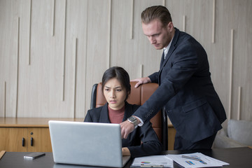 Upset woman being scolded by boss for working at office, Boss showing time for deadline job, woman with stressful concept.