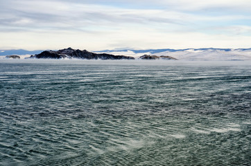 Ice floes floating on the fog water in the lake Baikal. Sunset