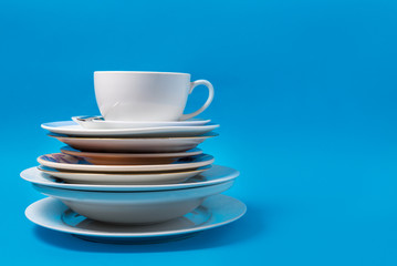 Pan, colander, plates and cup on blue background