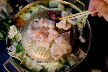 Hand with chopsticks for picking pork on the pan.
