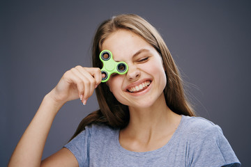 Beautiful young woman on a dark gray background holds a spinner