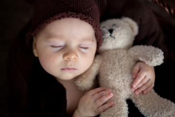 Cute three months old baby with bear hat in a basket, sleeping