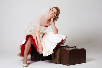 Sad bride with suitcases on white background in studio