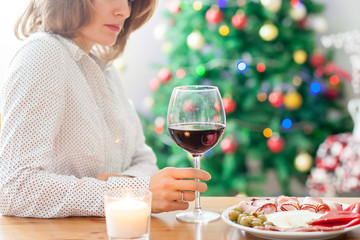 Young woman, drinking wine and having snack at home on christmas