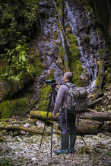 Professional photographer with cameras on tripod shooting in a river