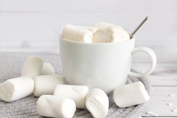 Marshmallow and a cup of hot cocoa in white cup on bright background, front view