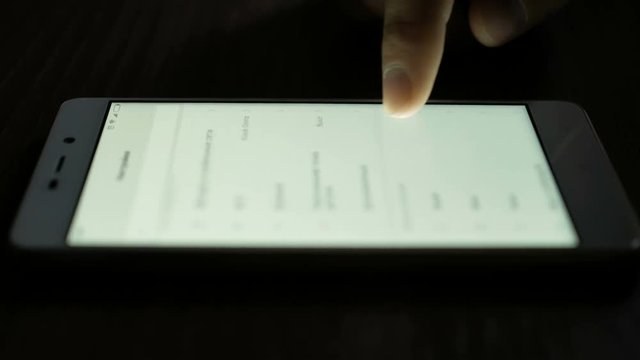 Use of smartphone in hands of close-up, menu scrolling is side view. Hand Scrolls smartphone settings.