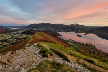 Beautiful subtle sunrise colours on a calm Autumn morning at the summit of Catbells overlooking Derwentwater in the English Lake District.