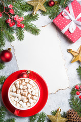 Christmas background frame or greeting xmas card. Hot chocolate with marshmallow, xmax present and decor on gray stone table. Top view with copy space.