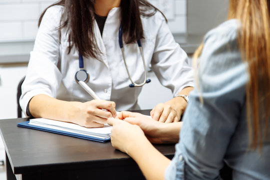 Close up of a female doctor filling up an application form while consulting patient