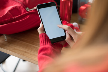 woman wearing red sweater using smartphone for social networking. girl typing text message on application in mobile phone. technology, communication
