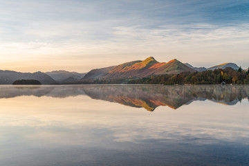 Morning golden light hitting mountains with calm reflections in lake. Taken at Derwentwater in the...