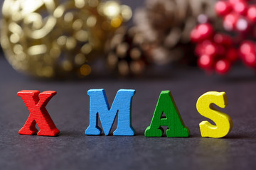 The concept of a New year, xmas. The word from multicolored letters on wooden Christmas background with gifts, pine cones, Christmas tree, candles. depth of field, selective focus