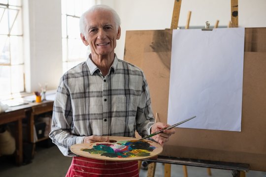 Portrait of smiling senior man holding color palette