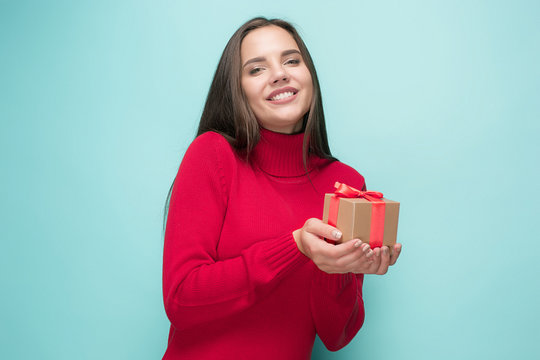 Portrait of happy young woman holding a gift isolated on white