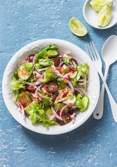 Salad with boiled chicken, tomatoes, cucumbers, lettuce, red onion and spicy ranch dressing on a blue background, top view