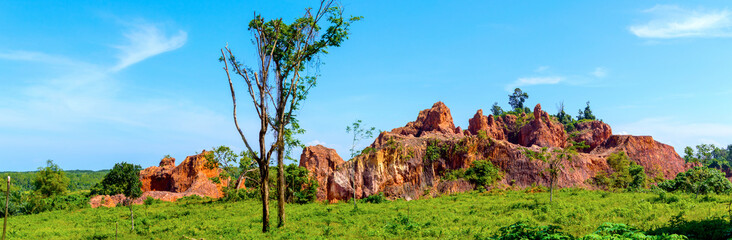 Cliffs and rocks in rural area in Thailand. Stone and grasses with flora. Panoramic view