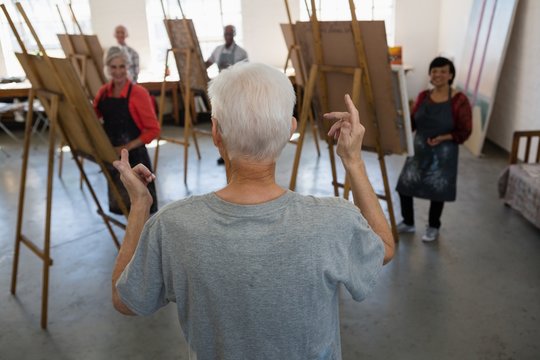 Senior man talking with artists in art class