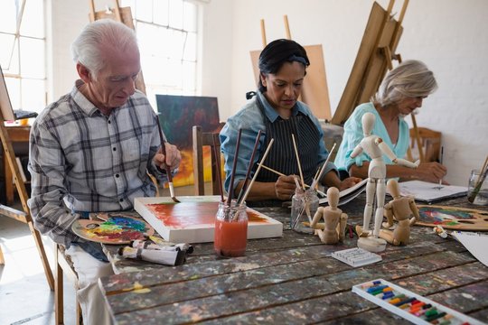 Senior male and female artists painting on canvas