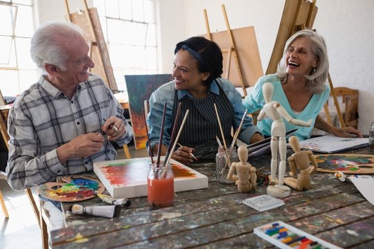 Cheerful senior male and female artists at table