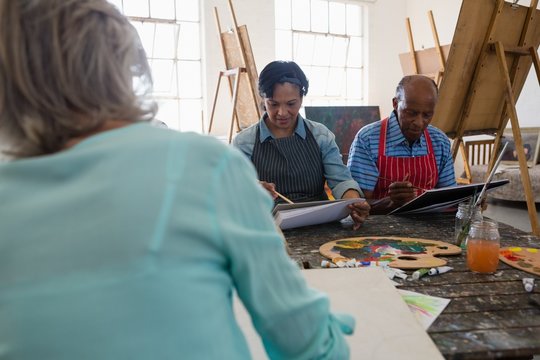 Senior male and female friends painting on canvas