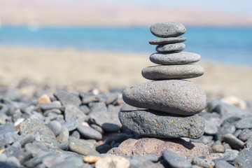 Obraz na płótnie Canvas Close-up of stack of stones in perfect balance on a tranquil sunny beach in Fuerteventura, SpainClose-up of stack of stones in perfect balance on a tranquil sunny beach in Fuerteventura, Spain