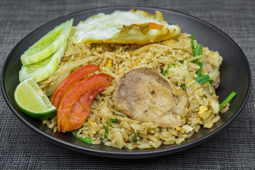 Fried rice with pork, lime, potato, cucumbers and fried egg in black plate