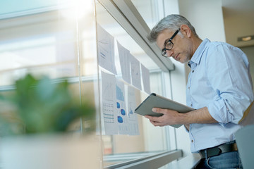 Businessman analyzing results charts hanged on office window