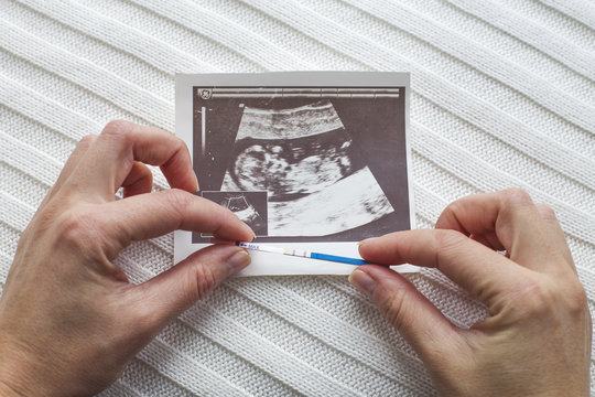 Women's hands with a pregnancy test and ultrasound photo