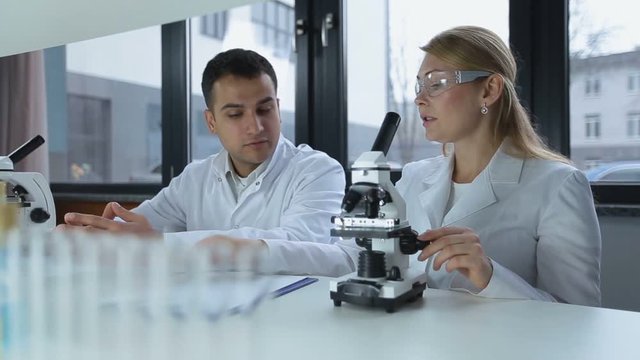 Researchers microscoping in biochemistry lab