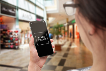 Woman use mobile phone for search for Black friday discounts. Black friday text on modern smartphone.