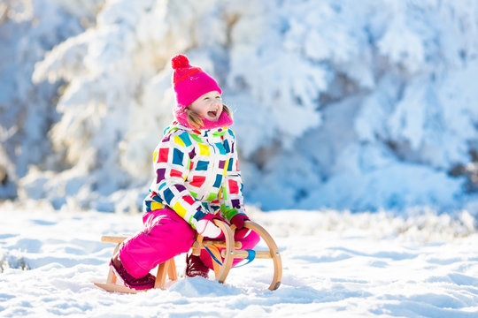 Girl on sleigh ride. Child sledding. Kid with sledge
