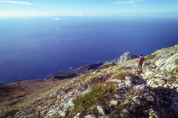 A man on top of a hill watching the beautiful scenery in the mountains during the autumn sunrise on...