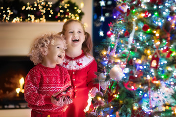 Children at Christmas tree. Kids at fireplace on Xmas eve