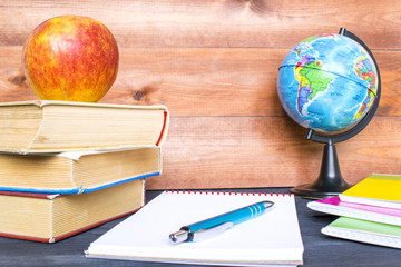 Studying concept, books, apple, globe and notebook on the wooden background.