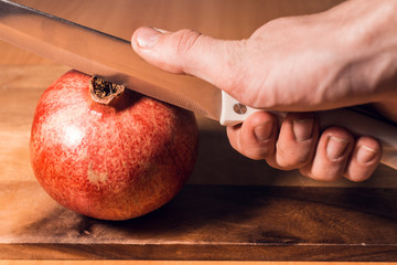 knife cuts a pomegranate on the board for cutting